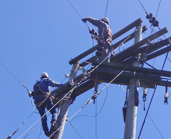 Trabajadores de líneas eléctricas en poste de distribución